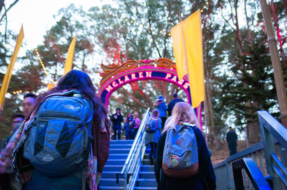 Image of two women wearing backpacks climbing stairs at a festival