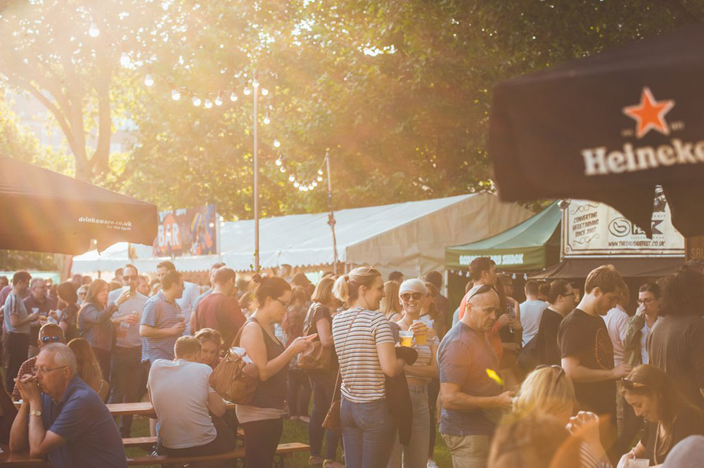 Image of people in a park chatting and sipping beer