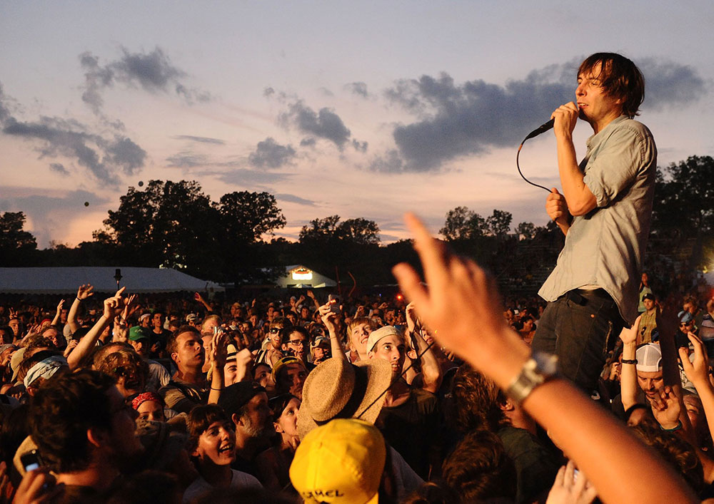 Image of white male singer holding a mic and addressing crowd